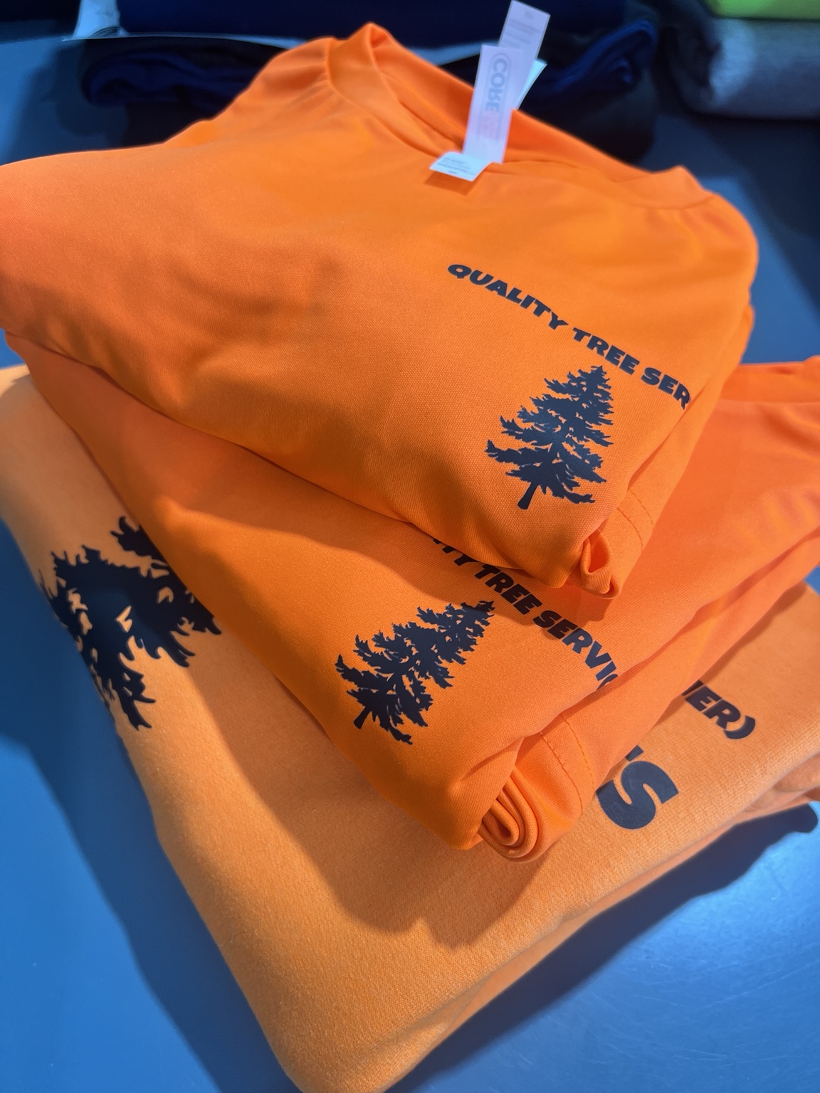 Orange Quality Tree Service shirts with black left-chest print
